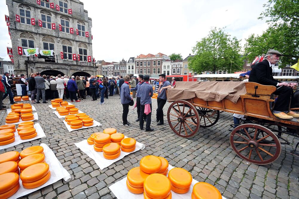 Kazen en een kaaswagen op de Goudse kaasmarkt, met publiek en historische gevels